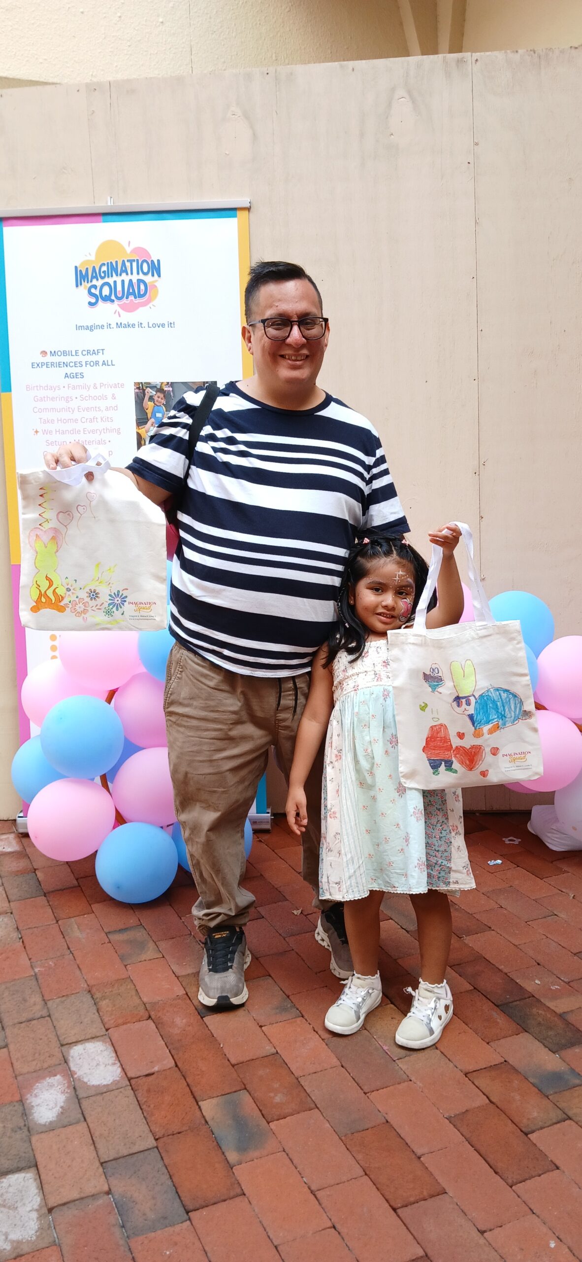 A family holding a creative project at an Imagination Squad event with pastel balloons